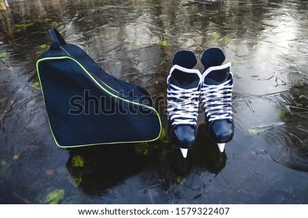 A pair of men's hockey skates stand on the lake and a bag for carrying skates. Royalty-Free Stock Photo #1579322407
