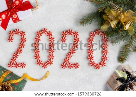 Christmas and New year frame made of fir branches, candies, gifts, and decorations. Christmas wallpaper. 2020 background isolated on white snow. Flat lay, top view, copy space.