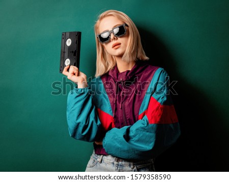 Style woman in 90s punk clothes wiith VHS cassette on aqua menthe color background