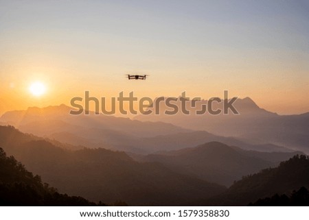 The drone with the professional camera takes pictures of the misty mountains at sunset. 