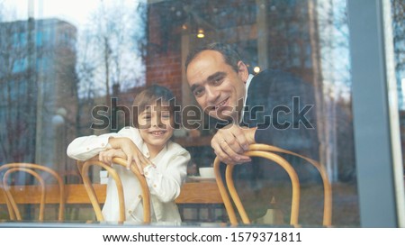Happy father and son look through the window in a cafe