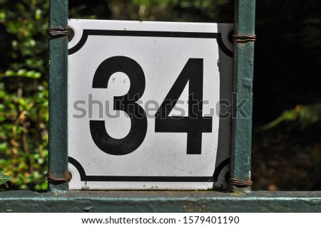 A house number plaque, showing the number thirty four (34)