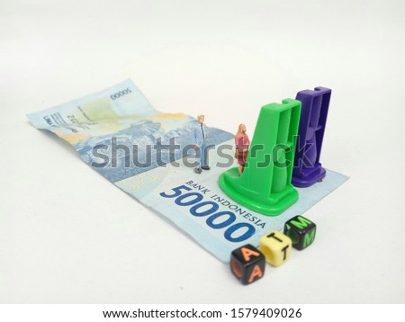 Simple Photo ilustration for Financial Transaction at Automatic Teller Machine, 50000  rupiah money as a floor, pencil sharpener as a ATM machine, with word from plastic cube bead, white back