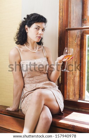 Pretty woman sit on sill and shake glass