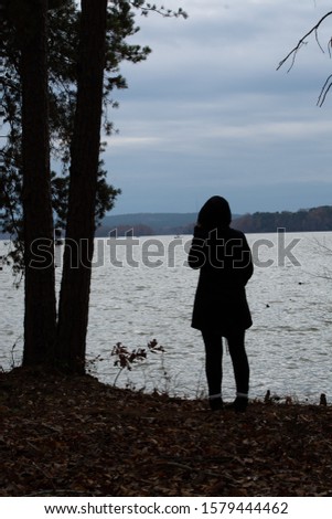 Woman looking out over lake from woods