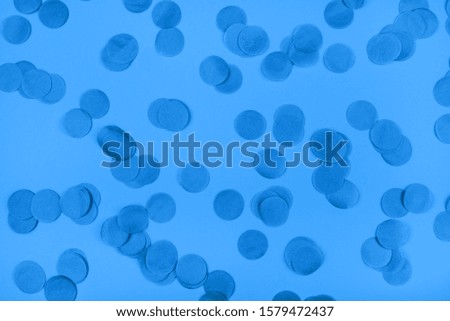 Blue confetti on blue background. Flat lay, top view. Color of year 2020.