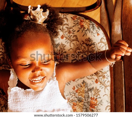 little cute african american girl playing at home, pretty adorable princess in interior happy smiling, lifestyle people concept