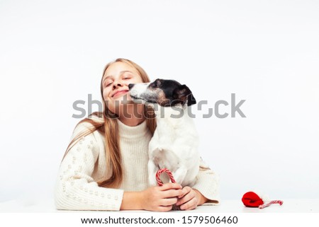 pretty young blond girl with her little cute dog wearing Santas red hat at Christmas holiday isolated on white background, lifestyle people concept