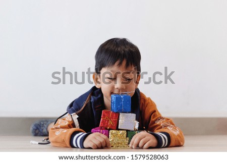Copy space and Portrait little Asian boy 5 year old picking and arrange colorful surprise gift boxes on the ground. Concept Birthday Kids and present box, Celebrate new year and Christmas Party. 
