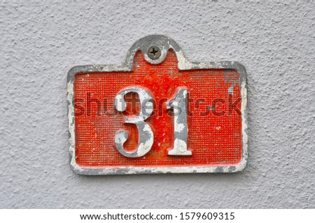 A house number plaque, showing the number thirty one (31)