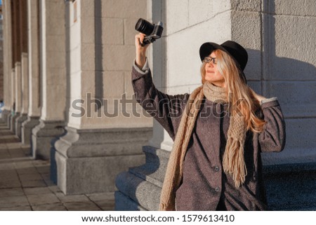 Portrait of a woman photographer. The girl takes a picture of the city on the camera.