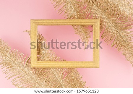 Luxury party festive background - golden sparkling palm branch and blank frame on pastel pink color backdrop, top view, copy space.