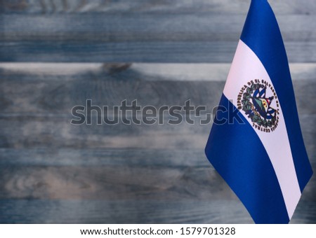 Fragment of the flag of the Republic of El Salvador in the foreground blurred light background copy space