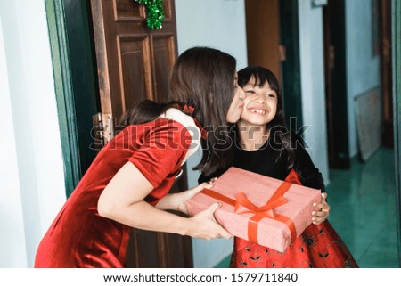 mother suprising her daughter with gift on christmas day. kiss