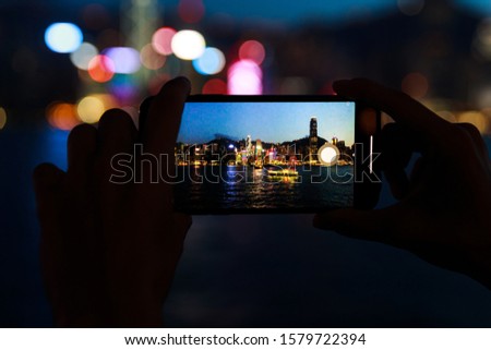Female hands with a smartphone. Taking picture of the night Hong Kong city.