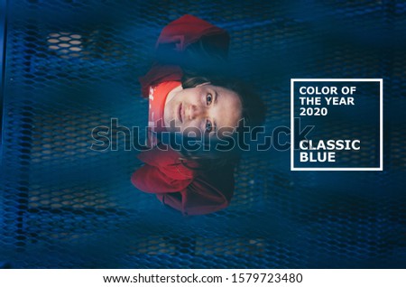 Color of the year 2020 Classic Blue pantone. Young woman in red mantle posing on blue background. Millennial concept.