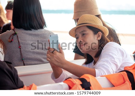 Female tourists using mobile phones to take pictures While traveling by boat