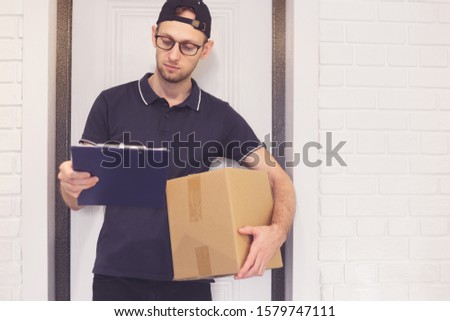 Portrait of a courier with a box of parcel and documents for signature.