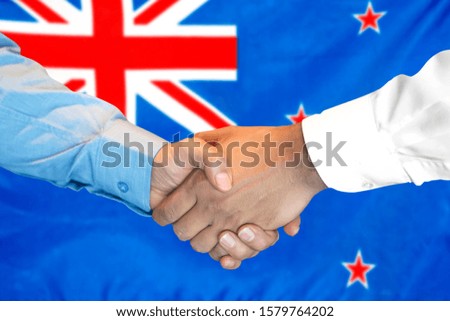 Business handshake on New Zealand flag background. Men shaking hands and New Zealand flag on background. Support concept