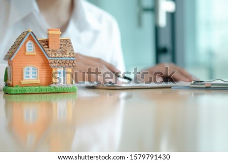 house model on back of real estate agents submit documents for customers to sign for a sale contract,real estate concept.