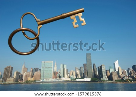 A large brass key suspended in the blue sky over a city skyline dotted with skyscrapers
