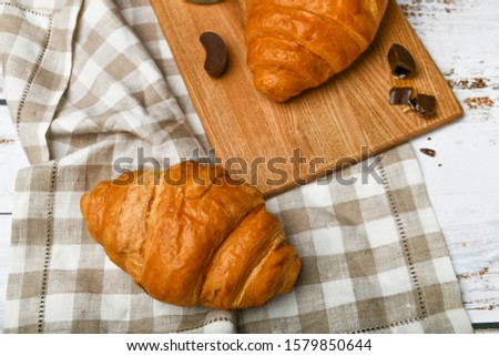 chocolate croissants. the beginning of the morning. A cup of coffee. Fresh french croissant. Coffee cup and fresh baked croissants on a wooden background. View from above.