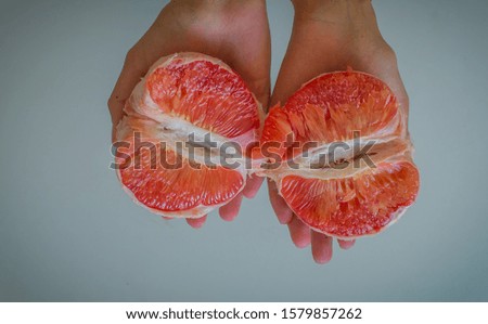 Two halves of grapefruit in women's hands
