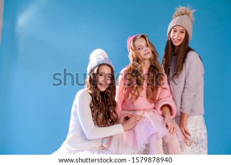 Three beautiful fashionable girl girlfriends in a winter snow cap