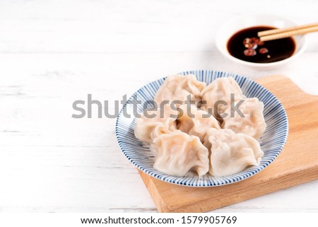 Fresh, delicious boiled pork gyoza dumplings, jiaozi on white background with soy sauce and chopsticks, close up, lifestyle. Homemade design concept. Royalty-Free Stock Photo #1579905769