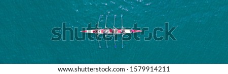 Aerial drone top down ultra wide panoramic view of sport canoe rowing synchronous athletes competing in tropical exotic lake Royalty-Free Stock Photo #1579914211