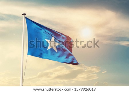 Somalia national flag cloth fabric waving on the sky with beautiful sun light - Image