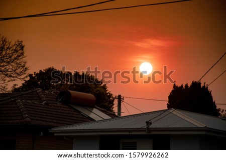 Australian bushfire: smoke from bushfires covers the sky and yellow and red sunset above the roofs looks frightening. Suburb in a smoke haze. Catastrophic fire danger, NSW, Australia Royalty-Free Stock Photo #1579926262