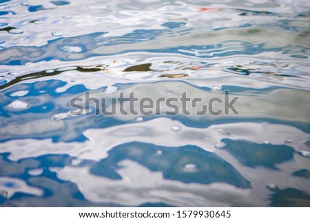 Colourful blue ripples on water with seaweed highlight