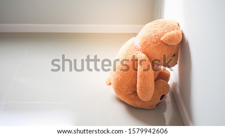 Child concept of sorrow. Teddy bear sitting leaning against the wall of the house alone, look sad and disappointed. Royalty-Free Stock Photo #1579942606