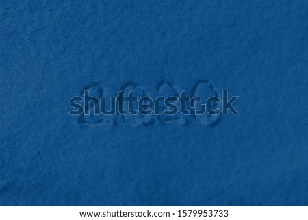 Color of the year 2020 classic blue. Text 2020 written on fresh snow in winter day. Merry Christmas and Happy New Year, winter holidays. Fashionable pantone color trend concept