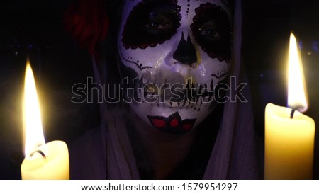 Halloween mask Catrina. Mexican day of the dead. Portrait of a young woman with scary makeup for Halloween on a dark background.