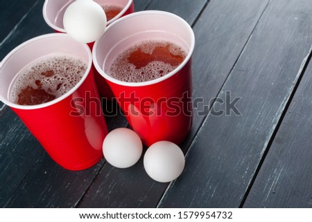 Wooden table with red cups and ball for beer pong