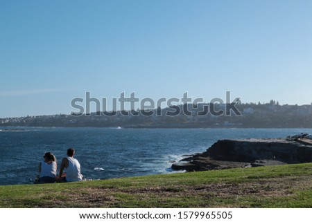 Couple sitting on the grass with an ocean and city views