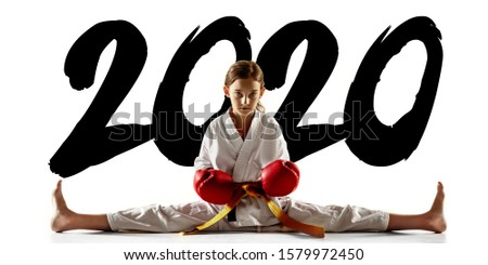 Confident junior in kimono practicing hand-to-hand combat, martial arts. Young female fighter with yellow belt's training on white studio background. Concept of healthy lifestyle, sport. Flyer, 2020.
