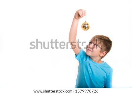 
the boy holds in his hands a Christmas tree toy of golden color, smiles. Christmas and New Year celebration. isolated on white background