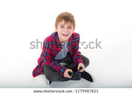 
boy has fun playing the phone. in a stylish shirt. isolated on white background