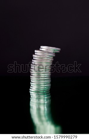 a large number of a pile of silver coins with a ribbed side, lie together, a close-up photo of real metal money of a green hue, because illuminated by green light
