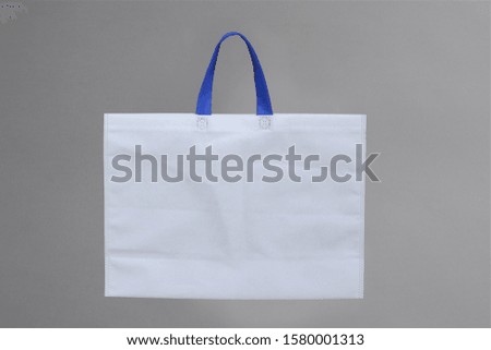 white eco bag with blue handle on gray background. environmentally concept. reusable shopping handbags 