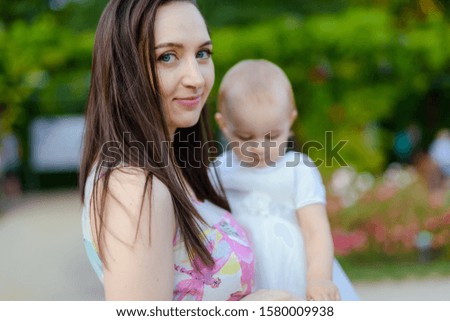 Happy mother and daughter in the park. Beauty nature scene with family outdoor lifestyle. Happy family resting together on the green grass, authentic lifestyle image