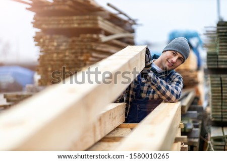 Young male worker in timber warehouse  Royalty-Free Stock Photo #1580010265