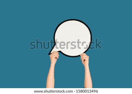 Hands holding the sign of comment on blue studio background. Negative space for text or image, advertising. Social media, showing meaning, communication, gadgets, modern technologies. Speech bubble.