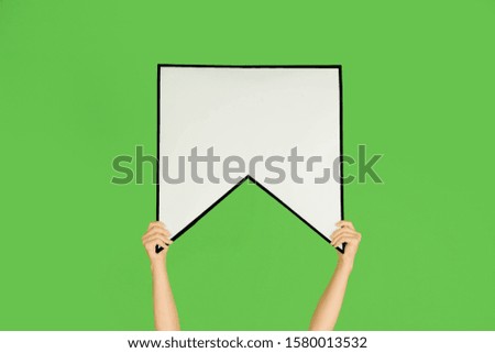 Hands holding the sign of bookmark on green studio background. Negative space to insert your text or image, advertising. Social media, meaning, communication, gadgets, modern technologies. Speech.