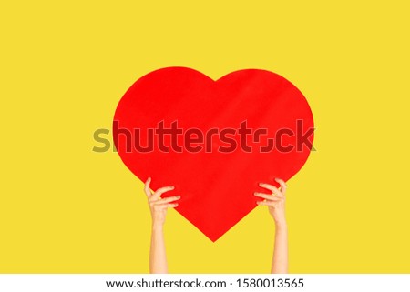 Hands holding the sign of heart on yellow studio background. Negative space to insert your text or image, advertising. Social media, showing meaning, communication, gadgets, modern technologies.