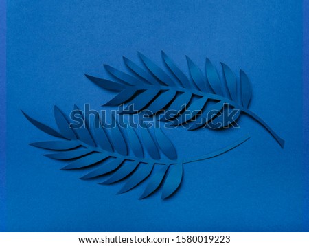 Hand made paper tropical Leaves toned in trendy blue color. Modern minimalist background. Color of the year 2020 classic blue.