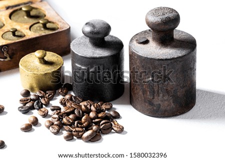 Old rustic metal weights with coffee beans on white background.